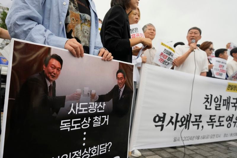 A protester holds a sign with a picture of South Korean President Yoon Suk Yeol, left, and Japanese Prime Minister Fumio Kishida during a rally opposing their planned meeting near the Presidential Office in Seoul, South Korea, Friday, Sept. 6, 2024. (AP Photo/Lee Jin-man)