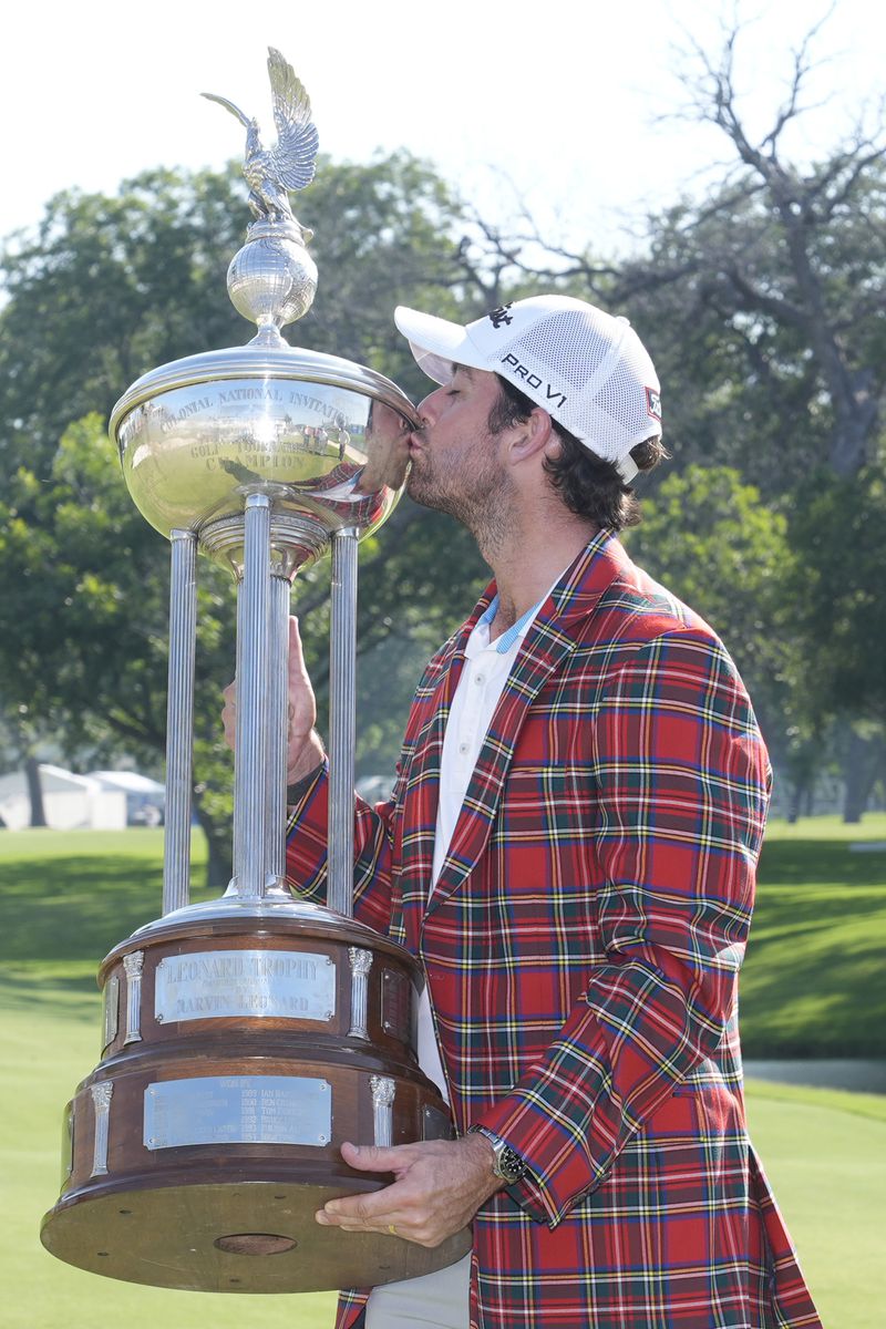 Davis Riley kisses the winner's trophy at the Charles Schwab Challenge golf tournament at Colonial Country Club in Fort Worth, Texas, Sunday, May 26, 2024. (AP Photo/LM Otero