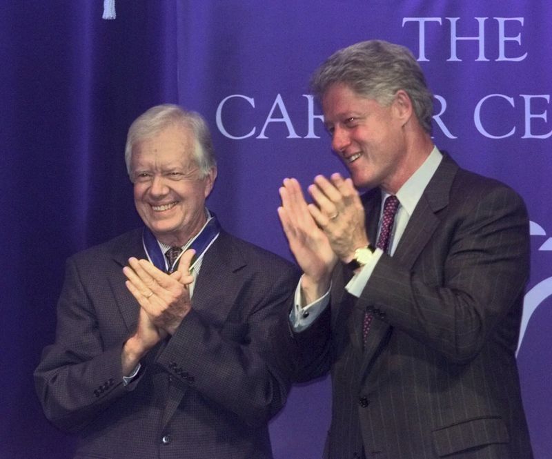 FILE - Former President Jimmy Carter and President Clinton applaud former first lady Rosalynn Carter as she speaks, after Clinton awarded the couple the Presidential Medal of Freedom, the nation's highest civilian honor, during a ceremony at the Carter Center in Atlanta, Aug. 9, 1999. (AP Photo/John Bazemore, File)