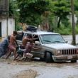 Residents work together to push a vehicle stuck on a street flooded by the passing of Hurricane John, in Acapulco, Mexico, Friday, Sept. 27, 2024. (AP Photo/Bernardino Hernandez)