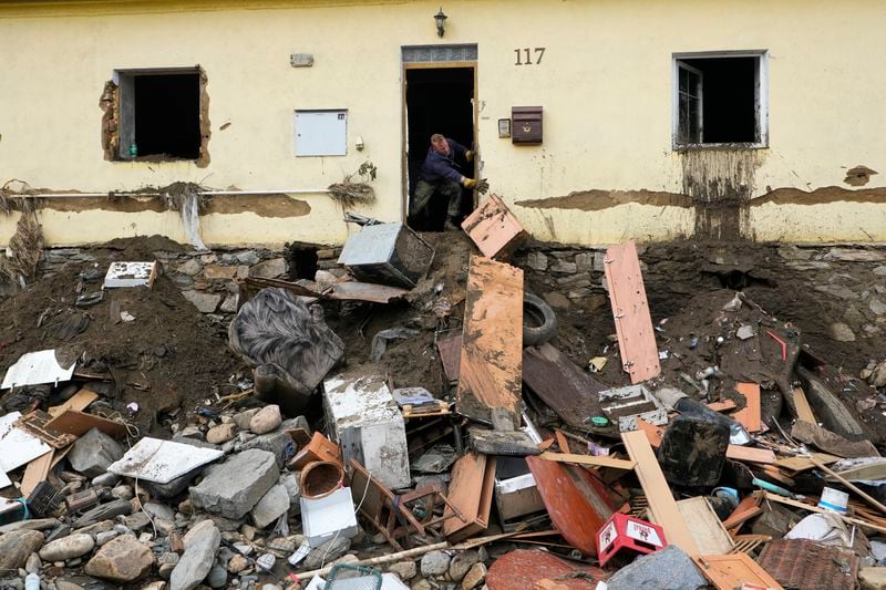 A man throws damaged goods and furniture off a house as residents return to clean up after recent floods in Mikulovice, Czech Republic, Thursday, Sept. 19, 2024. (AP Photo/Petr David Josek)