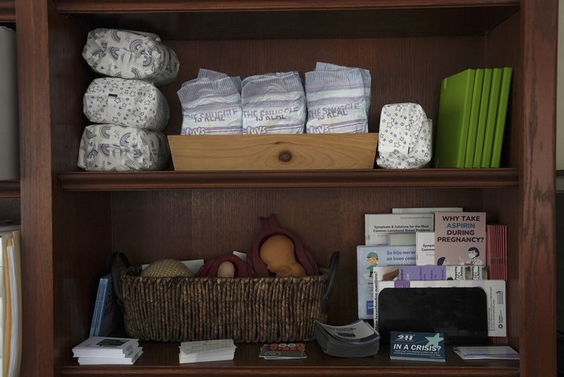 Baby supplies and educational materials sit on a shelf in the office of Krystal Keener, a Healthy Start care coordinator based at the Oklahoma State University obstetrics and gynecology clinic, in Tulsa, Okla., on Tuesday, July 16, 2024. (AP Photo/Mary Conlon)