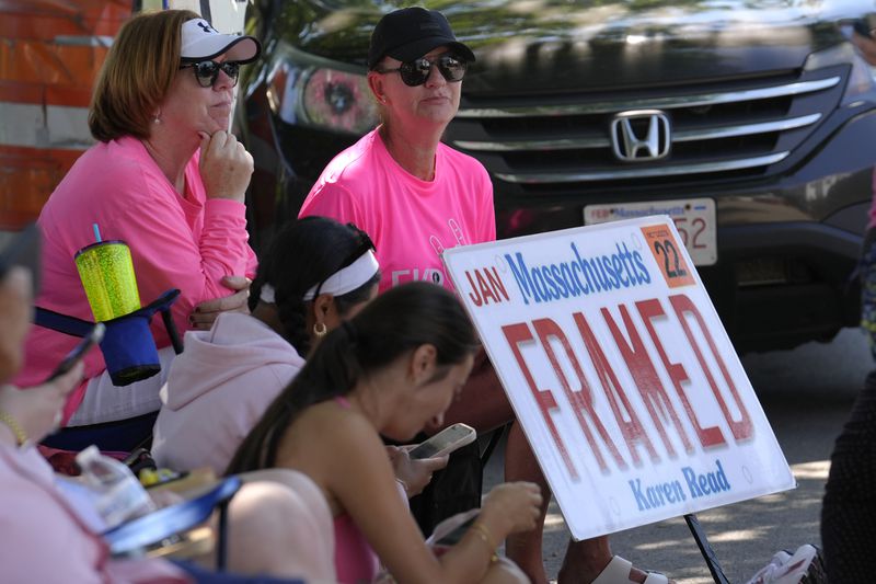 Lisa Hoffman, of Mansfield, Mass., right, displays a sign in support of Karen Read that features a likeness of a Massachusetts license plate, while seated a block away from Norfolk Superior Court, Tuesday, June 25, 2024, in Dedham, Mass. Karen Read is on trial, accused of killing her boyfriend Boston police Officer John O'Keefe, in 2022. (AP Photo/Steven Senne)