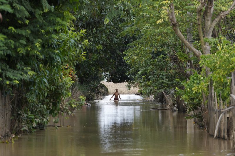 A boy wades through a flooded road, in Naypyitaw, Myanmar, Tuesday, Sept. 17, 2024. (AP Photo/Aung Shine Oo)