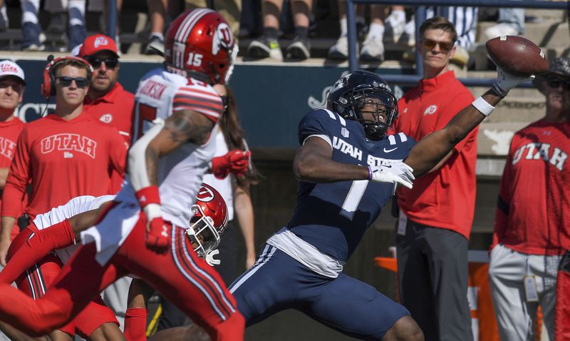 Utah State receiver Jalen Royals (1) catches a pass as Utah cornerback Zemaiah Vaughn (5), and safety Tao Johnson (15) defend in the first half of an NCAA college football game, Saturday, Sept. 14, 2024, in Logan, Utah. (Eli Lucero/Herald Journal via AP)