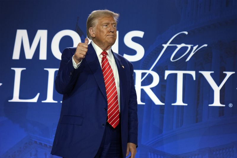 Republican presidential nominee former President Donald Trump gestures after speaking with Moms for Liberty co-founder Tiffany Justice during an event at the group's annual convention in Washington, Friday, Aug. 30, 2024. (AP Photo/Mark Schiefelbein)