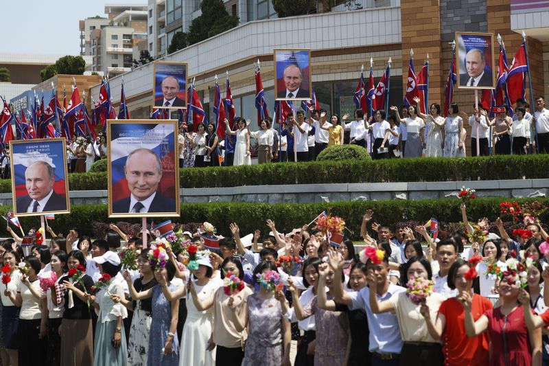 FILE - People, holding portraits of Russian President Vladimir Putin, greet and applaud as a motorcade with Russian President Vladimir Putin and North Korea's leader Kim Jong Un move past in a street in Pyongyang, North Korea, Wednesday, June 19, 2024. China appears to be keeping its distance as Russia and North Korea move closer to each other with a new defense pact that could tilt the balance of power between the three authoritarian states. (Gavriil Grigorov, Sputnik, Kremlin Photo via AP)