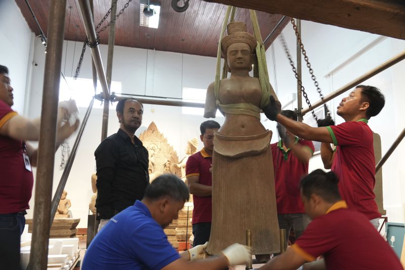 Museum staff members prepare an artifact returned from U.S to Cambodia, before an official ceremony at the Cambodian National Museum in Phnom Penh Cambodia, Thursday, July 4, 2024. Cambodia on Thursday officially organized a welcome ceremony for the arrival of more than a dozen rare Angkor era sculptures from New York's Metropolitan Museum of Art that were tied to an art dealer and collector accused of running a huge antiquities trafficking network out of Southeast Asia. (AP Photo/Heng Sinith)