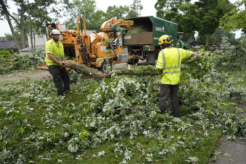 Work crews clean up Friday, June 21, 2024 in Beverly Hills, Mich., after straight-line winds ripped through tree-lined neighborhoods in portions of Oakland County late Wednesday, leaving residents without power and trees uprooted and tossed across entire streets. (AP Photo/Carlos Osorio)