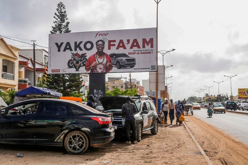 Cars are parked under a sign written in Wolof in Dakar, Senegal, Wednesday, Oct. 2, 2024. (AP Photo/Annie Risemberg)