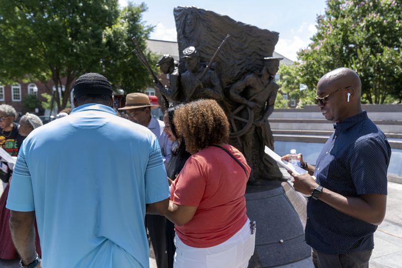 Associated Press reporter Darren Sands, right, reads the names of United States Colored Troops regimental soldiers, including his great-great-great-great grandfather Hewlett Sands, at the African American Civil War Memorial as part of Juneteenth commemorations on Wednesday, June 19, 2024, in Washington. (AP Photo/Mark Schiefelbein)