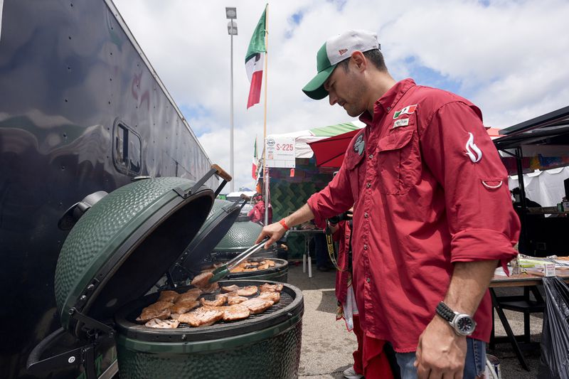 Marcelo Trevino of the Sociedad Mexicano de Parrillieros team checks meat on the grill at the World Championship Barbecue Cooking Contest, Friday, May 17, 2024, in Memphis, Tenn. (AP Photo/George Walker IV)
