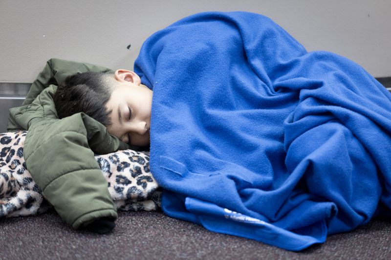  Jose Schneider takes a nap Saturday while he and his family wait for an answer to when their flight will depart Hartsfield-Jackson Atlanta International Airport. The father, Jose Luis, said they arrived in Atlanta  Friday and have yet to determine when they will be leaving.   (Steve Schaefer / AJC)