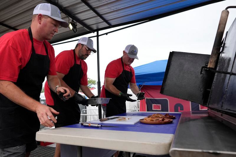 Members of the Pig Diamonds BBQ Team, Brent Little, left, Adriano Pedro, center, and John Borden, right, prepare a sample of whole hog for judges at the World Championship Barbecue Cooking Contest, Saturday, May 18, 2024, in Memphis, Tenn. The international team is comprised of members from Brazil and the United States. (AP Photo/George Walker IV)