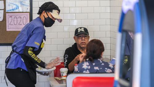 April 27, 2020 Brookhaven: Waffle House's Miss D (left) serves Daniel Bahena and his guest (right) on Monday, April 27, 2020 at The Waffle House at 2886 Clairmont Road in Brookhaven. Restaurants around metro Atlanta began to reopen dining rooms Monday, April 27, 2020 as restrictions related to the coronavirus pandemic are lifted. Restaurants will be allowed to operate with in-person dining as long as they follow a set of 39 guidelines laid out by the state government, which include a requirement that all employees wear masks, a maximum of 10 customers per 500 square feet of floor space and a maximum of six diners per table. JOHN SPINK/JSPINK@AJC.COM