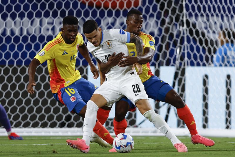 Uruguay's Maximiliano Araujo (20), is grabbed by Colombia's Carlos Cuesta, right, during a Copa America semifinal soccer match in Charlotte, N.C., Wednesday, July 10, 2024. (AP Photo/Nell Redmond)