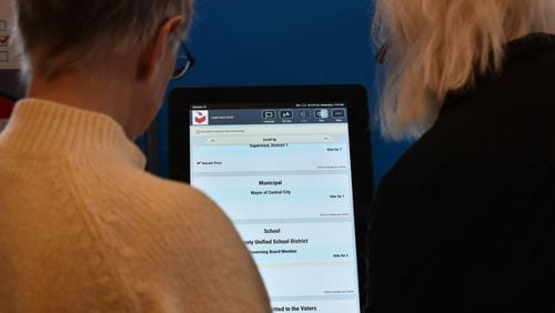 Event participants check out Dominion Voting Systems’ electronic voting system last January. HYOSUB SHIN / HSHIN@AJC.COM