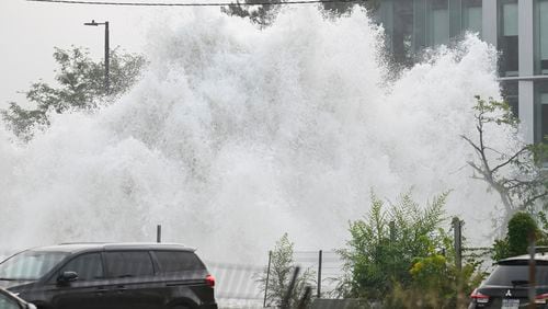 A broken water main spews water into the air on a street in Montreal, Friday, Aug. 16, 2024, causing flooding in several streets of the area. (Graham Hughes/The Canadian Press via AP)