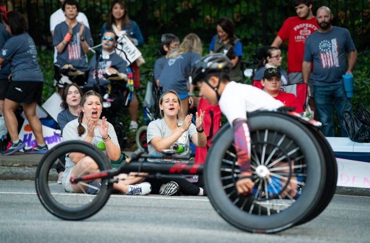 Spectators cheer on a participant in the wheelchair division of the 55th running of The Atlanta Journal-Constitution Peachtree Road Race at "Cardiac Hill" on Peachtree Road NW in Atlanta on Thursday, July 4, 2024. (Seeger Gray / AJC)
