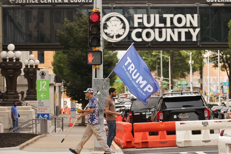 Ian Smith holds a Donald Trump flag as he passes the Fulton County Courthouse on Friday. 