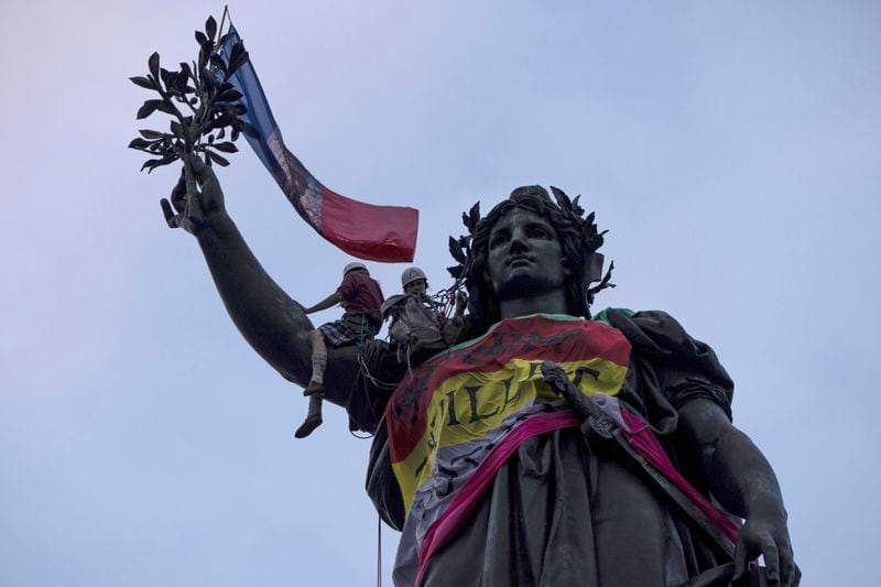 Statue of Republique plaza is decorated by flags as people gather at in a protest against the far-right, Wednesday, July 3, 2024 in Paris. French opposition parties and associations are trying to block a landslide victory for Marine Le Pen's far-right National Rally in next Sunday's second round of legislative elections. (AP Photo/Louise Delmotte)