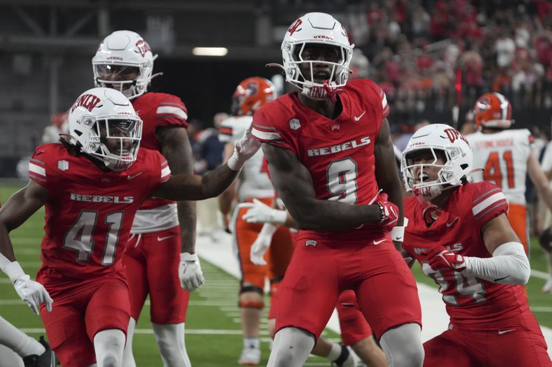 UNLV defensive back Jett Elad (9) celebrates with teammates after stopping the Syracuse offensive on fourth down in the first half during an NCAA college football game, Friday, Oct. 4, 2024, in Las Vegas. (AP Photo/Rick Scuteri)