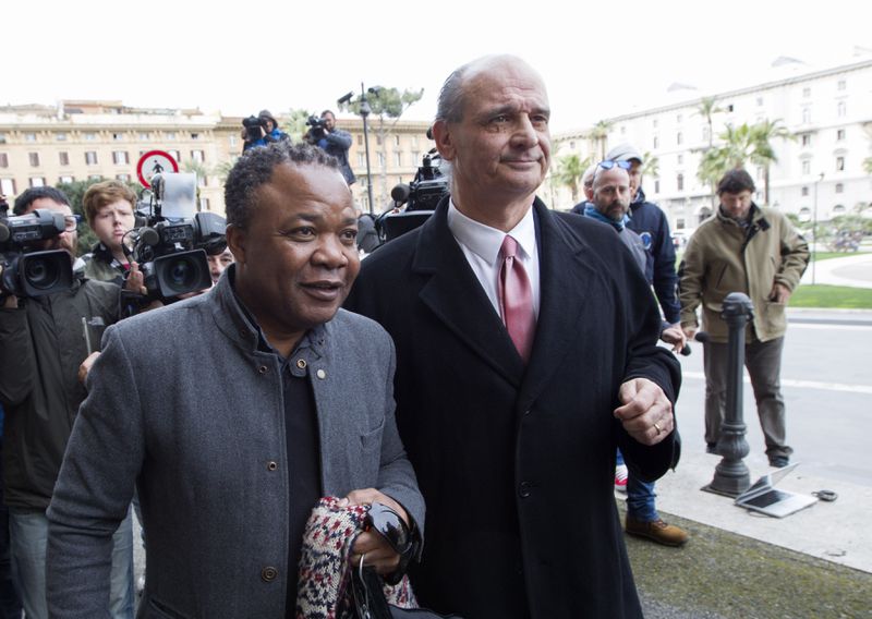 FILE- Diya "Patrick" Lumumba, left, a Congolese citizen who was accused by Amanda Knox and originally jailed for the murder of Meredith Kercher, flanked by his lawyer Carlo Pacelli, arrives at the Italy's highest court building, in Rome, Friday, March 27, 2015. Amanda Knox will be back in an Italian courtroom on Wednesday, June 5, 2024, to defend herself against a 16-year-old slander conviction that is the only charge against her that withstood five court rulings that ultimately cleared her in the brutal murder of her roommate, 21-year-old Meredith Kercher, in the apartment they shared in the idyllic central Italian university town of Perugia. (AP Photo/Riccardo De Luca, File)