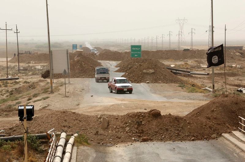 FILE - Islamic State militants passing a checkpoint bearing the group's trademark black flag in the village of Maryam Begg in Kirkuk, 290 kilometers (180 miles) north of Baghdad, Iraq, Sept. 29, 2014. Ten years after the Islamic State group declared its caliphate in large parts of Iraq and Syria, the extremists now control no land, have lost many prominent founding leaders and are mostly away from the world news headlines. (AP Photo/Hadi Mizban, File)