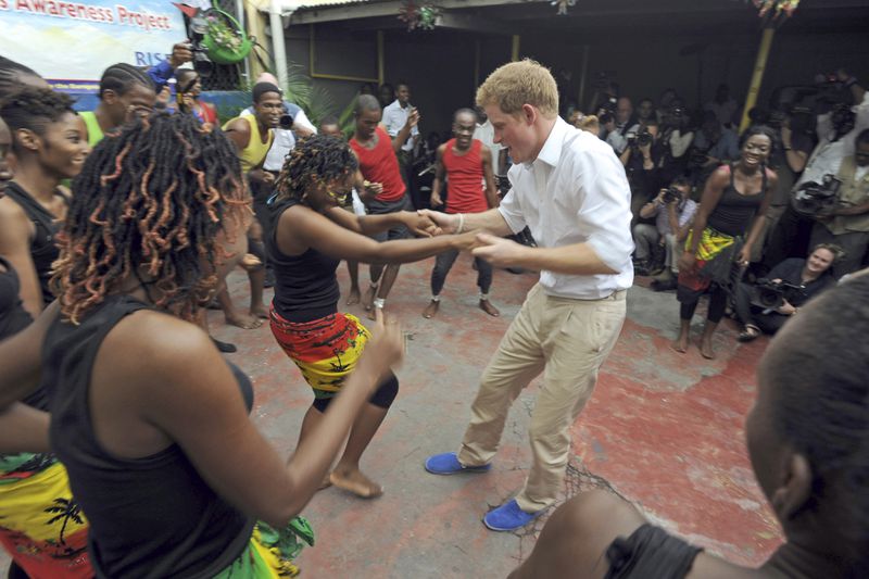 FILE - Britain's Prince Harry dances with a girl during a visit to the non-governmental organization RISE - Reaching Individuals through Skills and Education, in Kingston, Jamaica, Tuesday March 6, 2012. (AP Photo/Collin Reid, File)