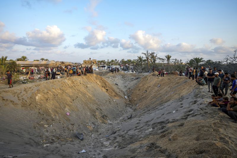 Palestinians look at the destruction after an Israeli airstrike on a crowded tent camp housing Palestinians displaced by the war in Muwasi, Gaza Strip, Tuesday, Sept. 10, 2024. An Israeli strike killed at least 40 people and wounded 60 others early Tuesday, Palestinian officials said. Israel said it targeted "significant" Hamas militants, allegations denied by the militant group. (AP Photo/Abdel Kareem Hana)