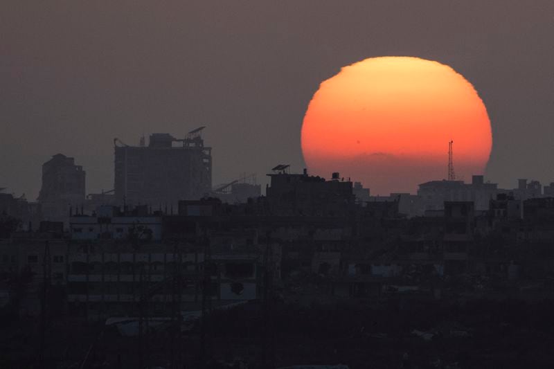 The sun sets behind the buildings in the Gaza Strip as seen from southern Israel, Saturday, June 29, 2024. (AP Photo/Leo Correa)