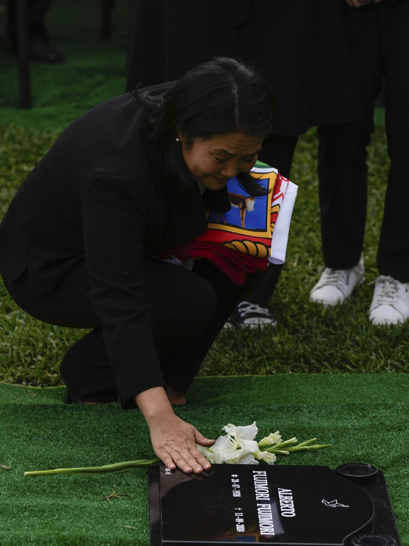 Keiko Fujimori places a flower over over the grave of her father, former President Alberto Fujimori, during his funeral n Lima, Peru, Saturday, Sept. 14, 2024. (AP Photo/Guadalupe Pardo)