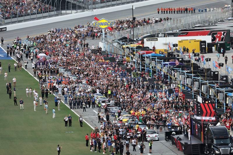 Drivers, crew members and guests stand on pit road for the national anthem before a NASCAR Cup Series auto race at Daytona International Speedway, Saturday, Aug. 24, 2024, in Daytona Beach, Fla. (AP Photo/David Graham)