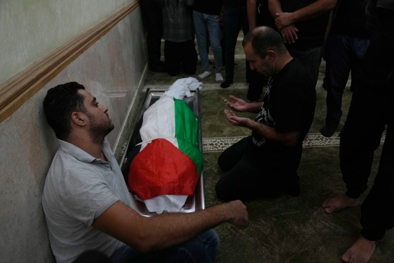 Mourners take the last look at the body of Sameh al-Asali, 38, a Palestinian worker from Gaza who had been stranded in the territory since the war broke out and was killed by a rocket during Tuesday's night's Iranian strike toward Israel, during his funeral in the West Bank city of Jericho, Wednesday, Oct. 2, 2024. (AP Photo/Nasser Nasser)