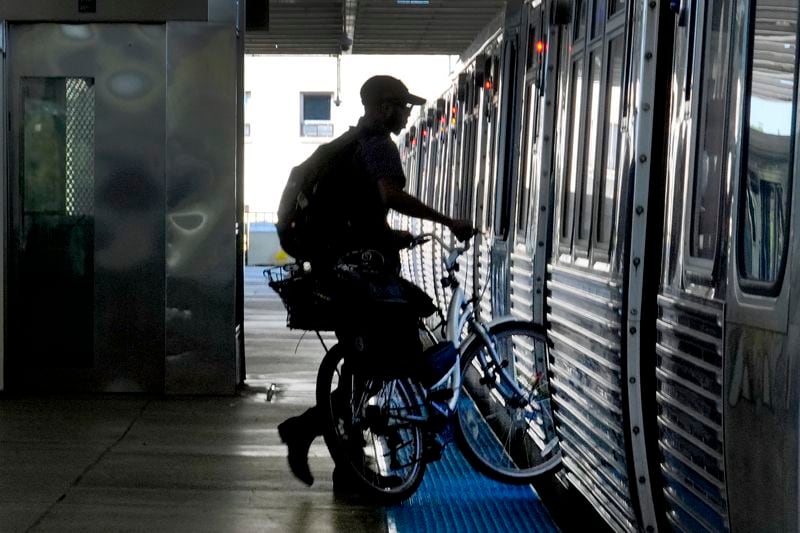 A cyclist enters a Chicago Transit Authority Blue Line train at the Forest Park., Ill., station headed East to Chicago, Tuesday, Sept. 3, 2024, in Forest Park. (AP Photo/Charles Rex Arbogast)