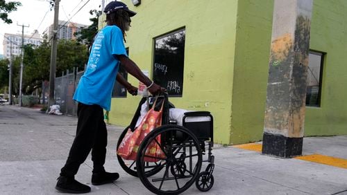 Robert Robinson, 61, who is homeless, pushes his belongings down the street on the first day of a statute that took effect, making it illegal in Florida to sleep on sidewalks, in parks, on beaches or in other public spaces — one of the country's strictest anti-homelessness laws, Tuesday, Oct. 1, 2024, in Fort Lauderdale, Fla. (AP Photo/Lynne Sladky)