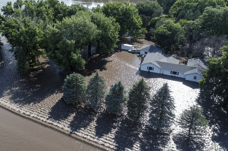 A home is surrounded by floodwaters, Saturday, June 22, 2024, south of Brandon, S.D., after days of heavy rain led to flooding in the area. (AP Photo/Josh Jurgens)