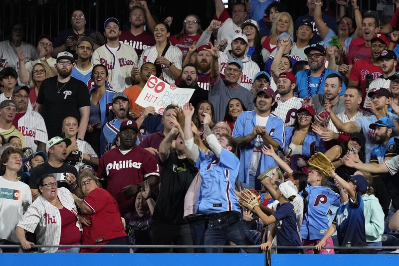 Fans reach for a home run hit by Philadelphia Phillies' Bryson Stott against Atlanta Braves pitcher Reynaldo López during the fourth inning of a baseball game, Friday, Aug. 30, 2024, in Philadelphia. (AP Photo/Matt Slocum)