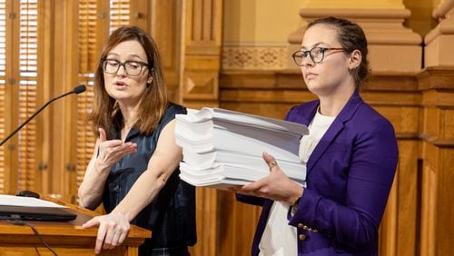 Kristin Nabers (left), state director for All Voting is Local, opposed a new rule seeking a hand count of ballots during a September meeting of the State Election Board at the Georgia Capitol as colleague Marissa Pyle holds 1,872 pieces of paper to demonstrate what a stack of ballots might look like. “Counting thousands of ballots by hand will be an incredibly tedious, expensive and possibly error-prone process,” Nabers said. “Any human errors can be exploited by election deniers to sow distrust and decrease confidence in our elections and in the hardworking election officials that run them.” (Arvin Temkar/AJC)