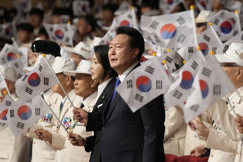 South Korean President Yoon Suk Yeol, center right, his wife Kim Keon Hee wave the national flags during a ceremony to mark the 74th anniversary of the outbreak of the Korean War in Daegu, South Korea, Tuesday, June 25, 2024. (AP Photo/Ahn Young-joon, Pool)