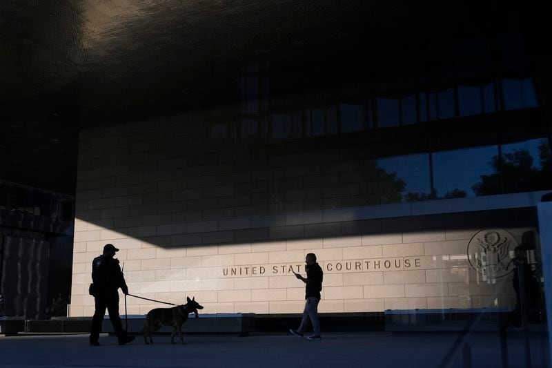 A police officer inspects the exterior of a federal courthouse with the aid of a canine at the start of Hunter Biden's trial on felony tax charges Thursday, Sept. 5, 2024, in Los Angeles. (AP Photo/Jae C. Hong)