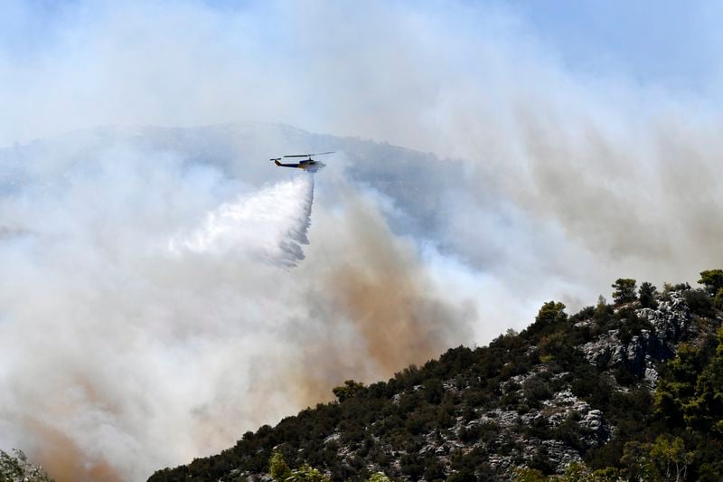 A helicopter drops water over a fire in Nea Makri, east of Athens, Monday, Aug. 12, 2024, as hundreds of firefighters tackle a major wildfire raging out of control on fringes of Greek capital. (AP Photo/Michael Varaklas)