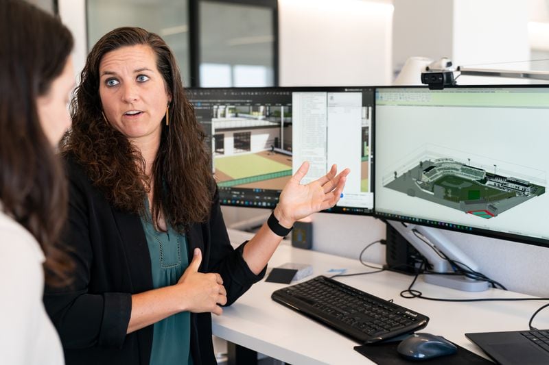 Meggie Meidlinger, a pitcher for Team USA women's baseball team and an architect at HKS, shows her work on an expansion for the University of Georgia's baseball stadium to Abigail Jablon, an architecture student at Rice University at the HKS office in Atlanta on June 26, 2024. (Seeger Gray / AJC)