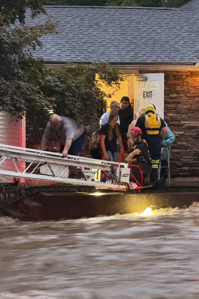 This photo provided by Beacon Hose Co. No. 1, a fire station in Beacon Falls, Connecticut, shows members of Beacon Hose Co. rescuing people from the Brookside Inn in Oxford, Conn., Sunday, Aug. 18, 2024. (Beacon Hose Co via AP)