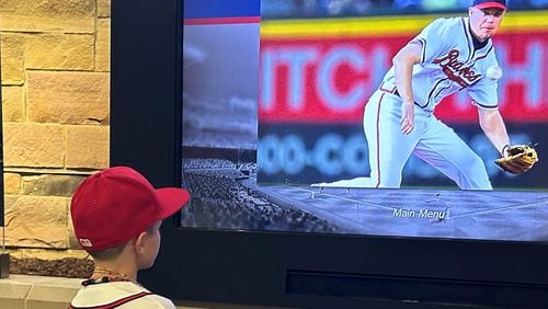 Baylor Skelton, age 8, whose favorite Braves player is Hall of Fame third baseman Chipper Jones, watches video of Jones on  a screen at Monument Garden at Truist Park on July 23, 2024. (Photo by Daniela Ramirez/The Atlanta Journal-Constitution)