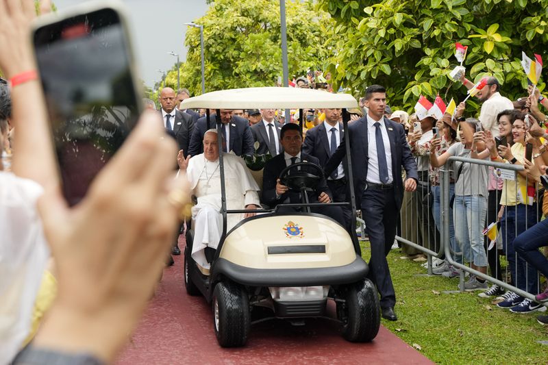 Pope Francis travels in a buggy as he greets the volunteers on his arrival in Singapore, Wednesday, Sept. 11, 2024. (AP Photo/Vincent Thian)