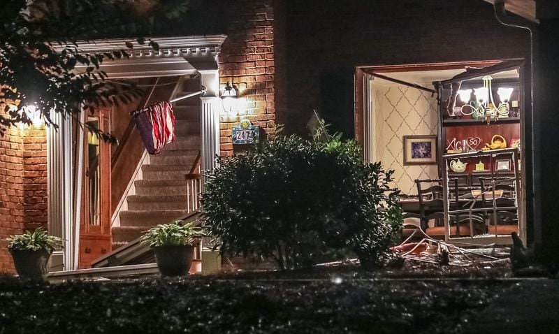 The front door and multiple front windows were busted out of their frames at a home on Hampton Glen Court, where an investigation continued Friday. Cobb County authorities engaged two suspects in an hourslong standoff the night before after two sheriff's deputies were shot and killed.