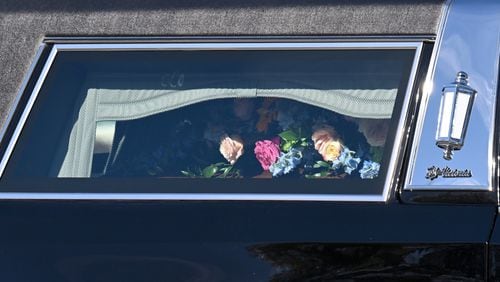 The casket of former first lady Rosalynn Carter is covered in flowers in the hearse outside the Rosalynn Carter Health & Human Services complex at Georgia Southwestern State University, Monday, November 27, 2023, in Americus. (Hyosub Shin / Hyosub.Shin@ajc.com)