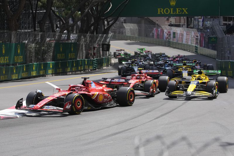 Ferrari driver Charles Leclerc of Monaco, left, leads the field after the start during the Formula One Monaco Grand Prix race at the Monaco racetrack, in Monaco, Sunday, May 26, 2024. (AP Photo/Luca Bruno)