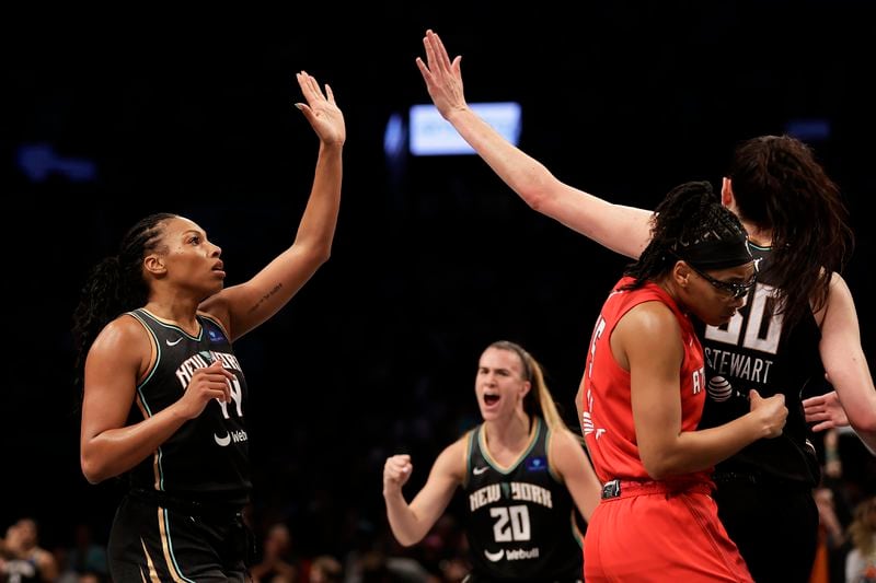 New York Liberty forward Betnijah Laney-Hamilton (44) high-fives Breanna Stewart, right, as Liberty guard Sabrina Ionescu (20) looks on while Atlanta Dream guard Allisha Gray ducks away during the first half of a first-round WNBA basketball playoff game, Tuesday, Sept. 24, 2024, in New York. (AP Photo/Adam Hunger)